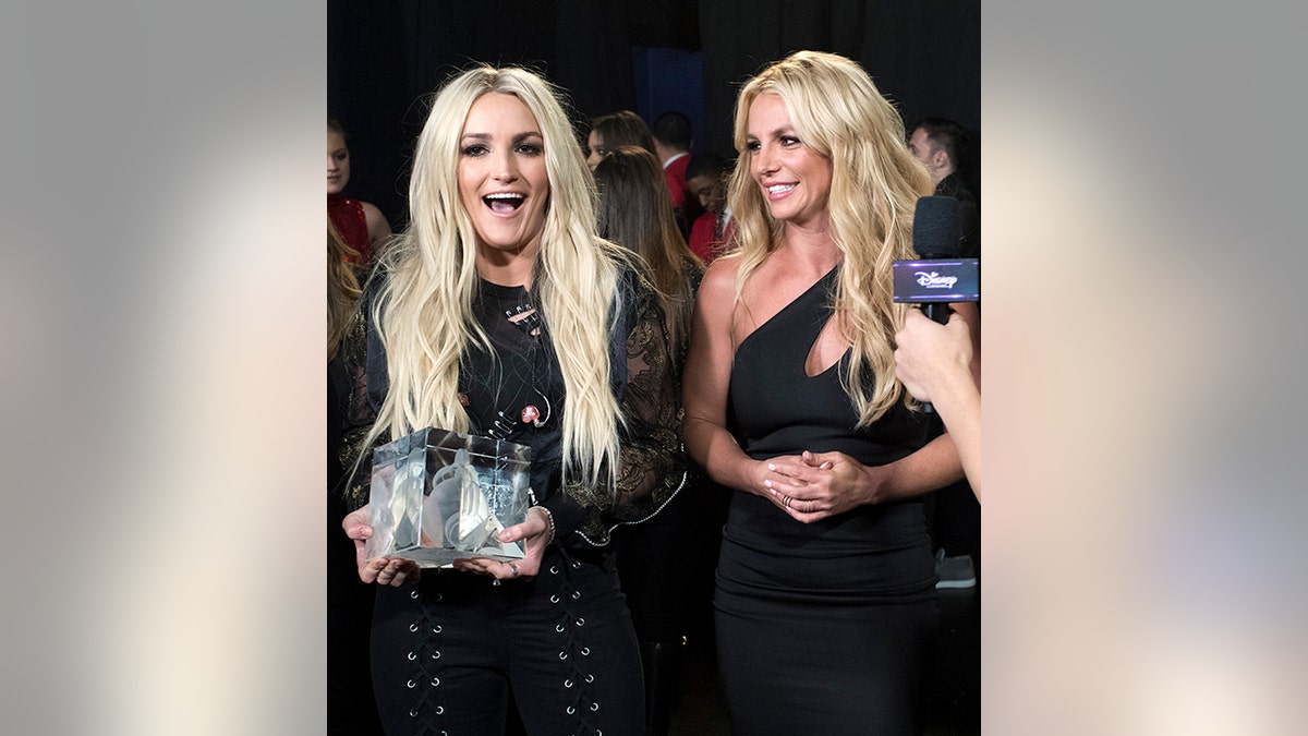 Jamie Lynn Spears lacht, als sie neben ihrer Schwester Britney steht, die beide Schwarz tragen