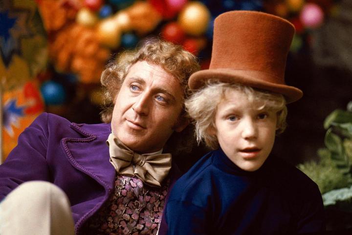 Willy Wonka sits next to a young boy.