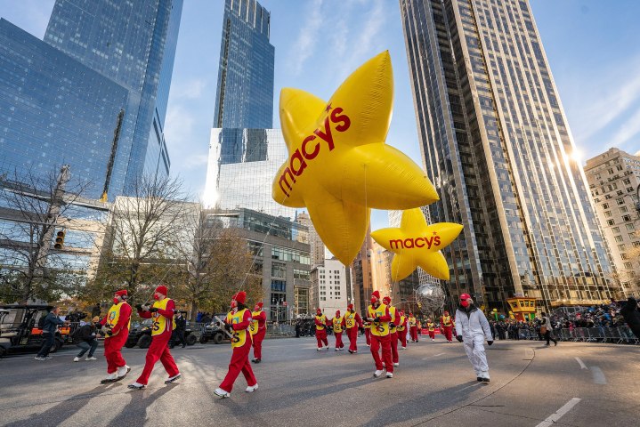 Zur Thanksgiving Day Parade marschieren Menschen mit einem großen Ballon durch die Straßen.