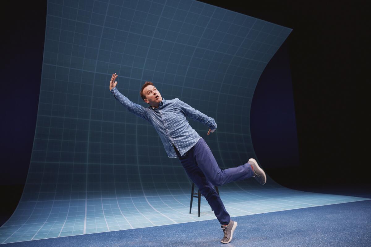 Ein Mann posiert vor blauem Hintergrund auf der Bühne, als würde er umfallen