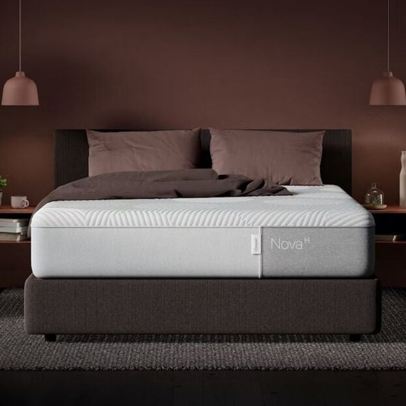 Die Casper Nova Hybrid-Matratze (Queen) auf einem grauen Bettgestell in einem schwach beleuchteten Schlafzimmer.