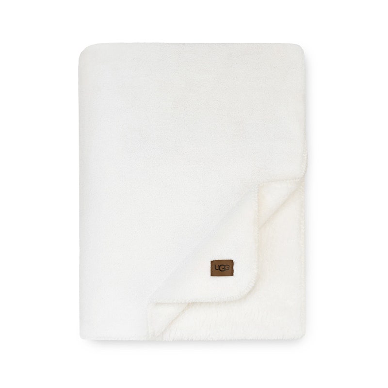 Eine weiße Ugg Whistler-Überwurfdecke auf weißem Hintergrund
