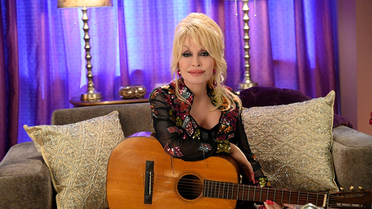 Dolly Parton sitzt mit ihrer Gitarre