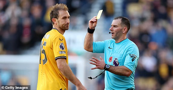 WOLVERHAMPTON, ENGLAND - NOVEMBER 11: Referee Tim Robinson shows a yellow card to Craig Dawson of Wolverhampton Wanderers during the Premier League match between Wolverhampton Wanderers and Tottenham Hotspur at Molineux on November 11, 2023 in Wolverhampton, England. (Photo by Catherine Ivill/Getty Images)