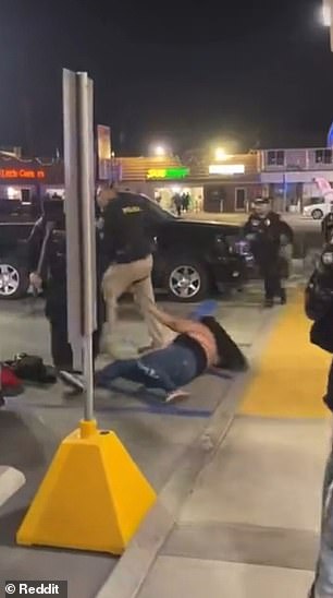 Die Frau versuchte sich aufzurichten, nachdem sie zu Boden gedrückt worden war, wurde jedoch von einem Polizisten festgehalten
