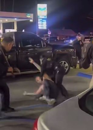 Eine Polizistin rannte herbei, um einem anderen Polizisten zu helfen, den männlichen Kunden festzuhalten, der sich im Polizeigewahrsam wand, nachdem sie begonnen hatten, ihn mit Stöcken zu schlagen