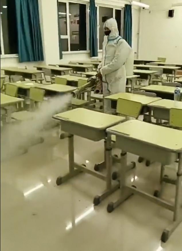 In Schutzanzügen, Handschuhen und Masken werden die Mitarbeiter gezeigt, wie sie zwischen den Schreibtischen in Klassenzimmern, Fluren und sogar im Freien gehen und dabei einen Nebel sterilisierender Flüssigkeit abgeben