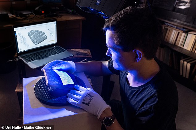 Ernst Stötzner führt einen 3D-Scan einer alten Keilschrifttafel durch und trägt dabei Handschuhe, um das jahrtausendealte Objekt zu schützen
