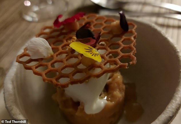 Eine „Kreation aus Quitte, fermentiertem Honig und Crème fraîche, präsentiert mit niedlichen kleinen essbaren Blüten auf einer Honigtülle“