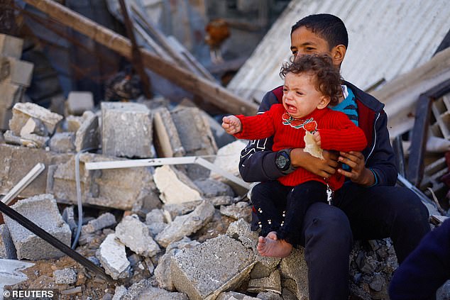 A child cries near the destroyed houses in Khan Younis, Gaza, on Thursday