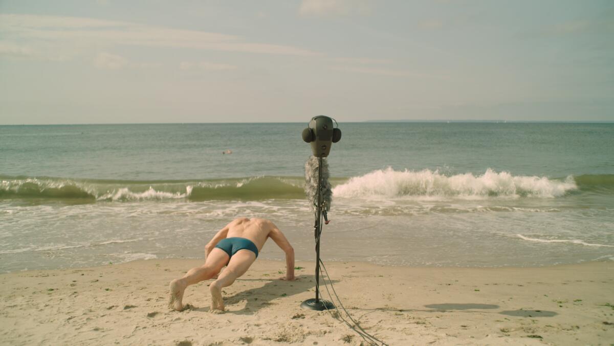 Ein Mann macht Liegestütze an einem Strand in der Nähe von Tongeräten "32 Klänge."