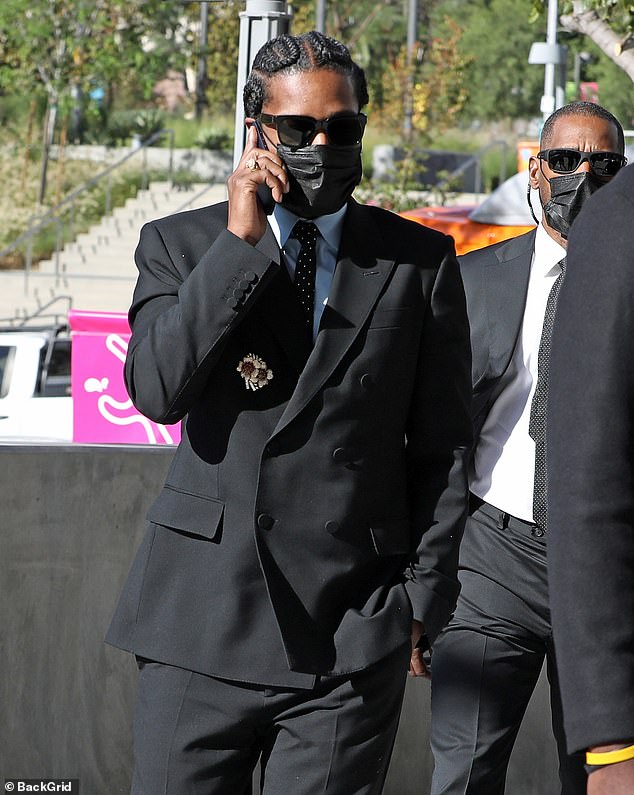 A$AP Rocky erschien am Montag in einem schwarzen Anzug, einer passenden schwarzen Gesichtsmaske, einer schwarzen Krawatte mit weißen Punkten und einer Blumenbrosche vor Gericht