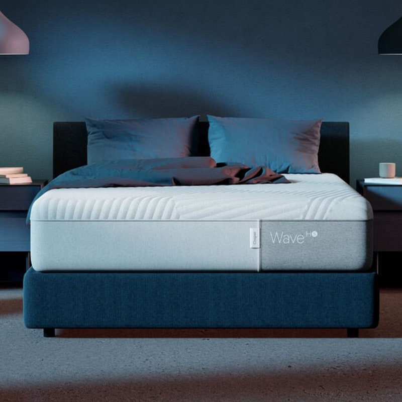 Die Casper Wave Hybrid-Schneematratze (Queen) auf einem Bettgestell in einem schwach beleuchteten Schlafzimmer