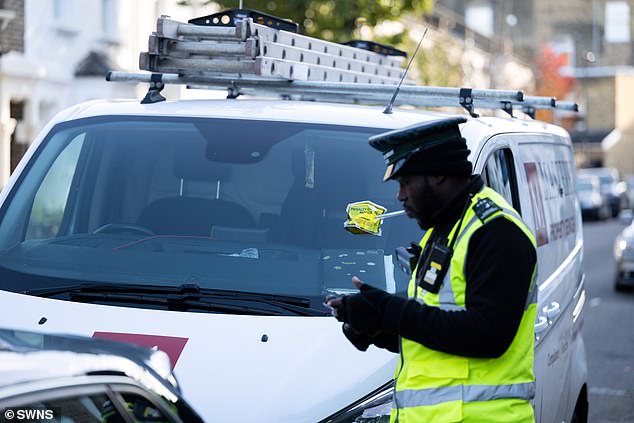 Bei einem Verkehrspolizisten, der einen Strafzettel für einen Lieferwagen ausstellt, der im Schatten des Emirates-Stadions von Arsenal geparkt ist, wo Autofahrer zusätzlich zur Grundparkgebühr von 2,50 bis 6,30 £ pro Stunde eine Dieselabgabe von 6,50 £ pro Stunde zahlen müssen