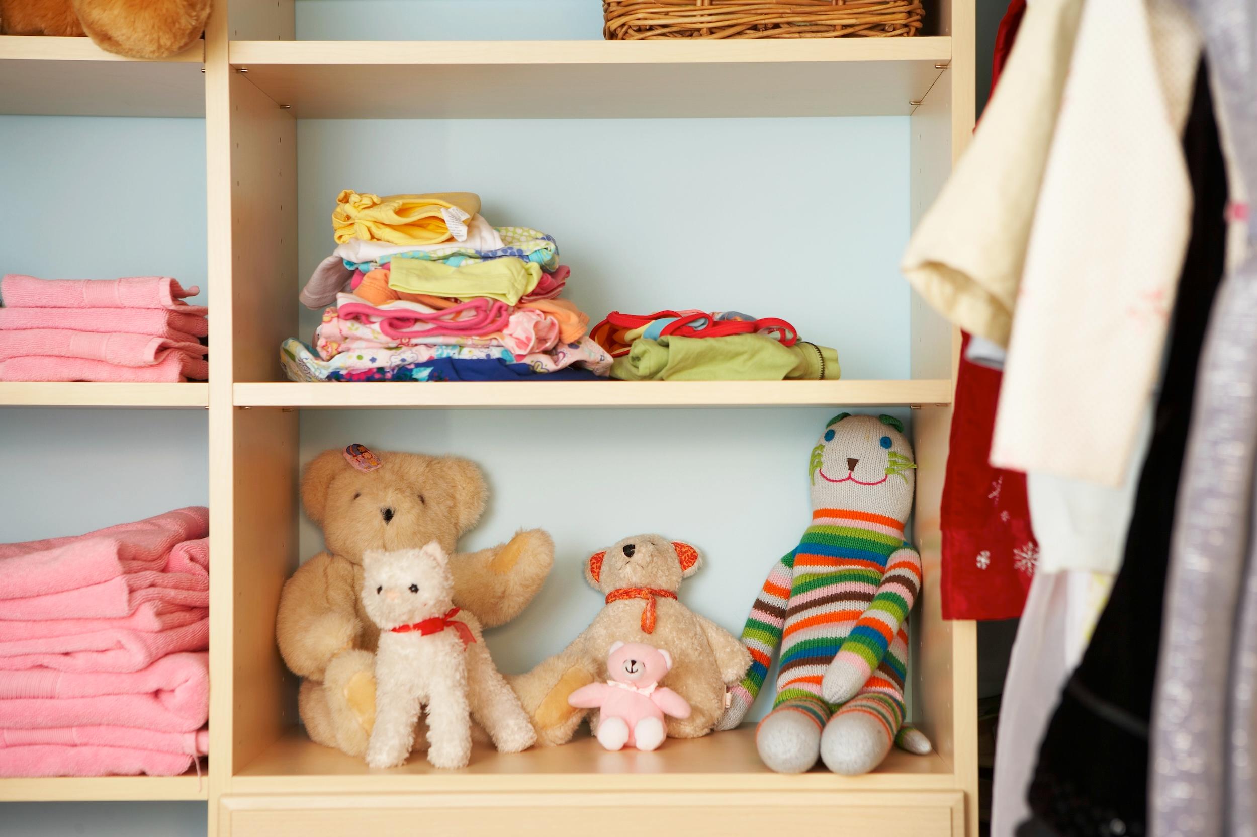 Kuscheltiere, Kleidung und Handtücher auf Regalen in einem Kinderzimmerschrank