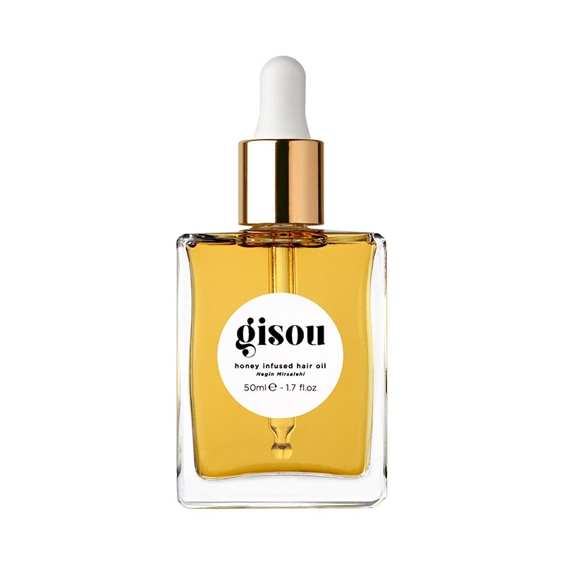 Gisou Honey Infused Hair Oil: Eine quadratische Tropfflasche aus Glas, gefüllt mit goldfarbenem Haaröl auf weißem Hintergrund