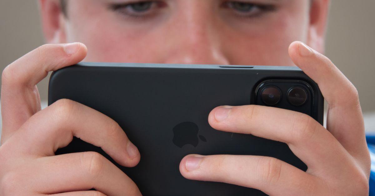   Ein 12-jähriger Junge schaut auf den Bildschirm eines iPhones