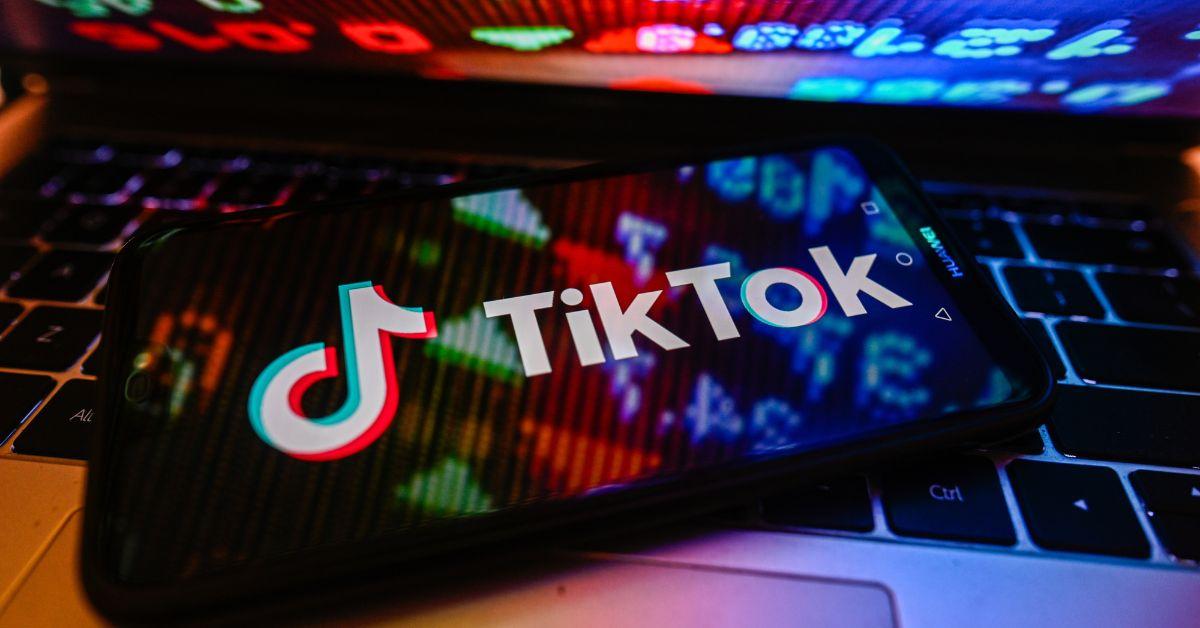 TikTok auf einem iPhone-Bildschirm mit Reflexionen vom Laptop