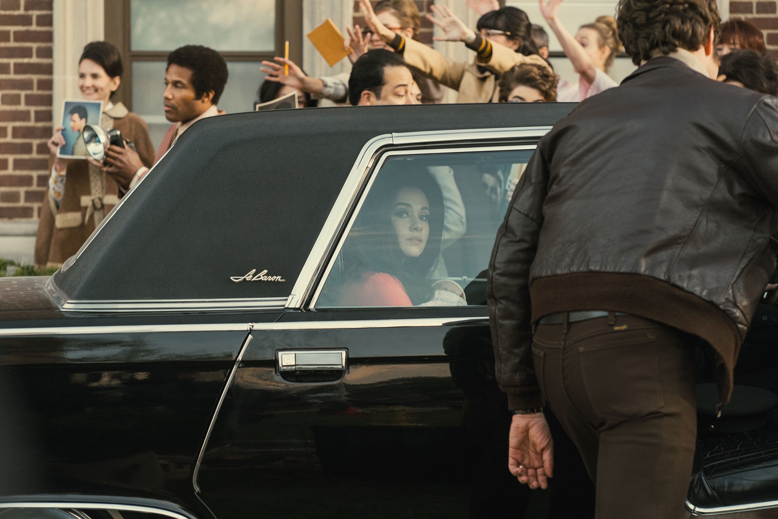 Cailee Spaeny als Priscilla Presley in Priscilla.  Sie sitzt auf der Rückbank eines Autos mit vielen Fans außerhalb des Fahrzeugs.