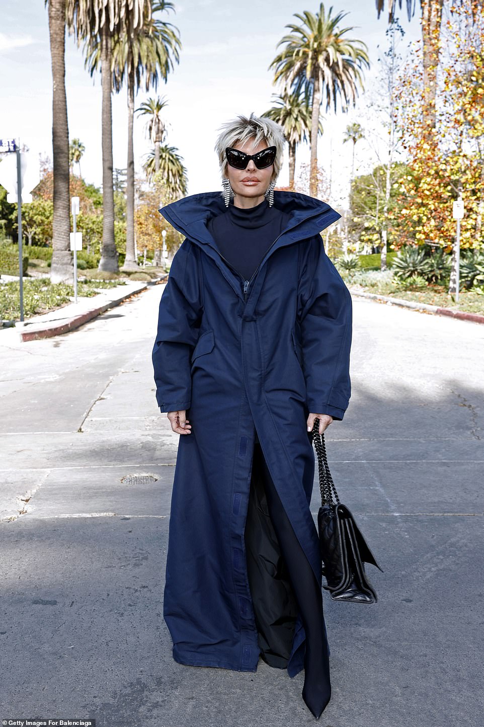 For the show, the Real Housewives of Beverly Hills alumna donned a floor-sweeping, deep blue raincoat-style trench coat over a turtleneck top and black pantaleggings