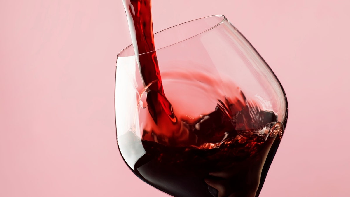 Rotwein wird in Glas gegossen stockbild