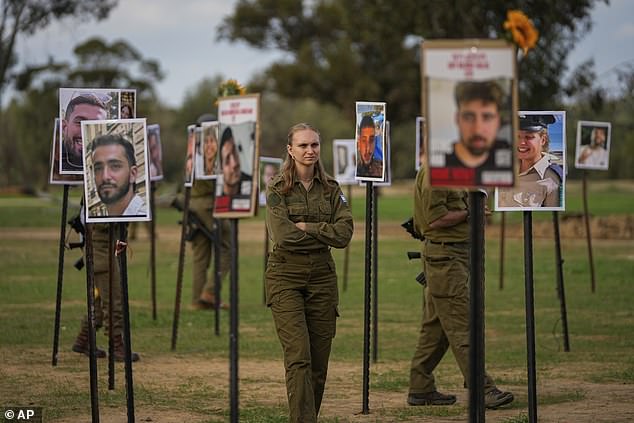 Israeli soldiers look at photos of people killed and taken captive by Hamas terrorists during their violent rampage through the Nova music festival in southern Israel on October 7