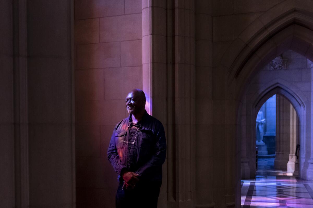 Der Künstler Kerry James Marshall steht vor einem sanft beleuchteten gotischen Bogen in der Washington National Cathedral