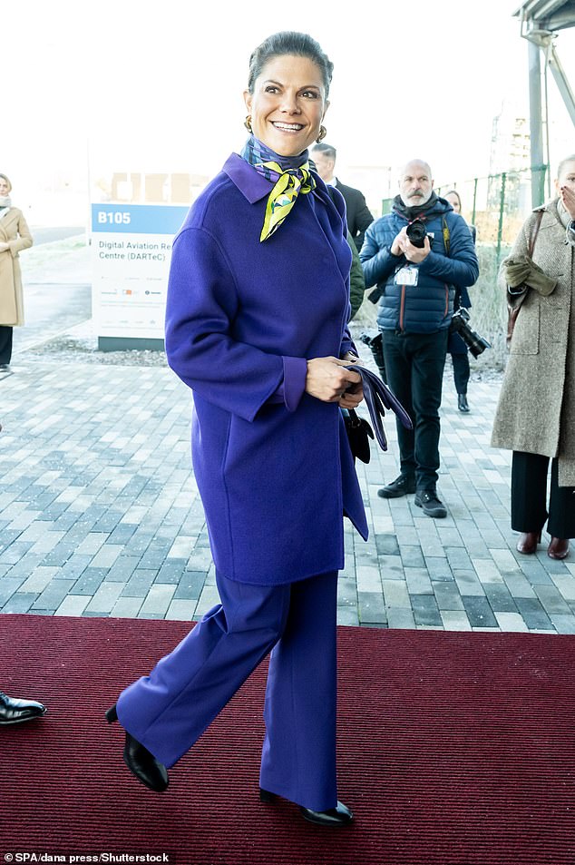 Victoria sah in einer mittellangen Jacke mit violettem Kragen elegant aus, während eine passende, gerade geschnittene Hose, ein Baumwollhemd und Lederhandschuhe das Ensemble abrundeten