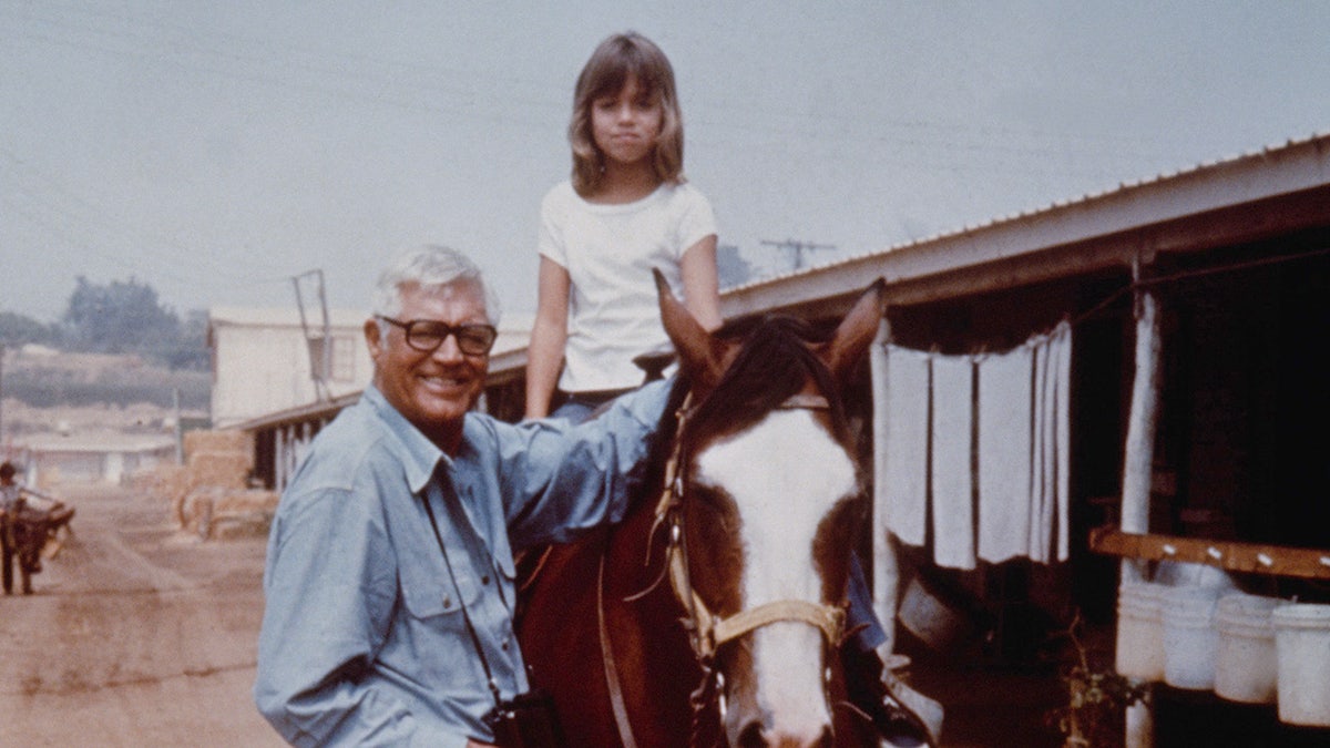 Jennifer Grant auf einem Pferd neben einem lächelnden Cary Grant