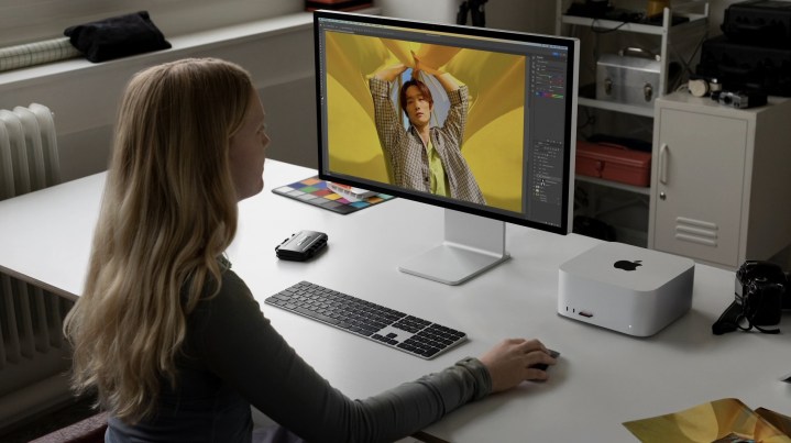 Eine Frau sitzt an einem Schreibtisch mit dem M2 Mac Studio darauf.
