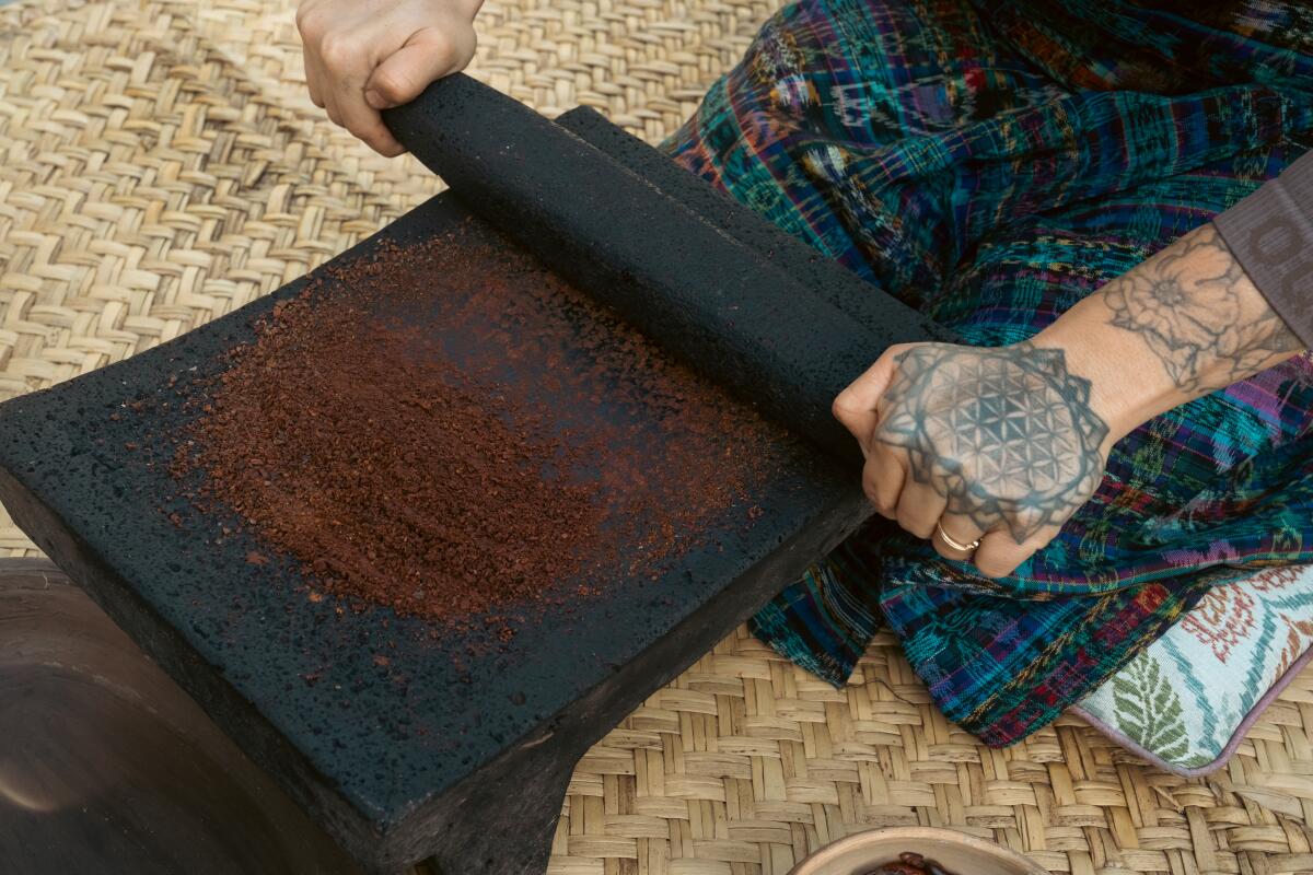 Nach dem Schälen werden jeweils kleine Mengen Kakaosamen auf einem traditionellen Metat aus Vulkangestein gemahlen.