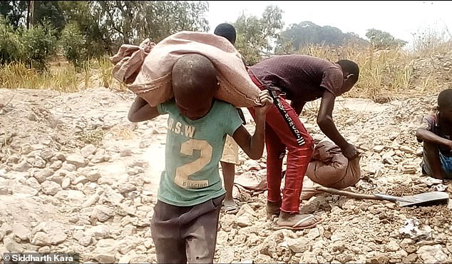 Auch Kinder bleiben in den „handwerklichen“ Minen der Demokratischen Republik Kongo nicht von den Strapazen der Handarbeit verschont.  Oben trägt ein Kind einen Sack voller Steine ​​in Kapata, südwestlich von Kolwezi