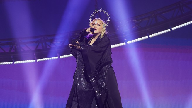 Ein Bild von Madonna, die in einem schwarzen Gewand auf der Bühne singt