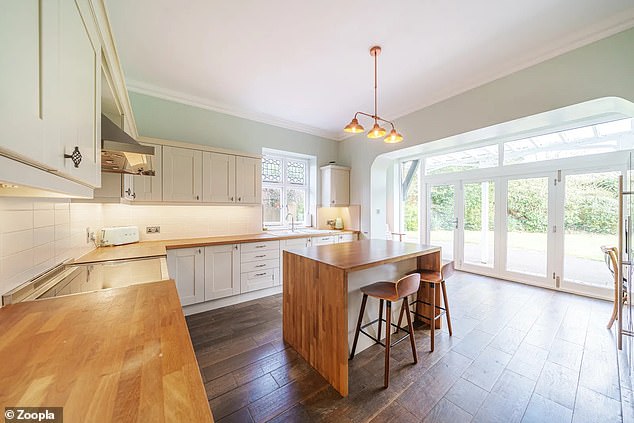 Die Küche verfügt über elfenbeinfarbene Unter- und Wandschränke und große Terrassentüren, die ins Freie führen