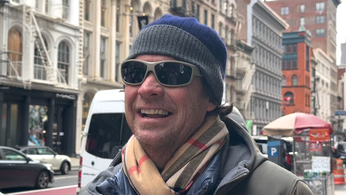 Mann steht auf Bürgersteig in New York und redet über Weihnachtsgeschenke