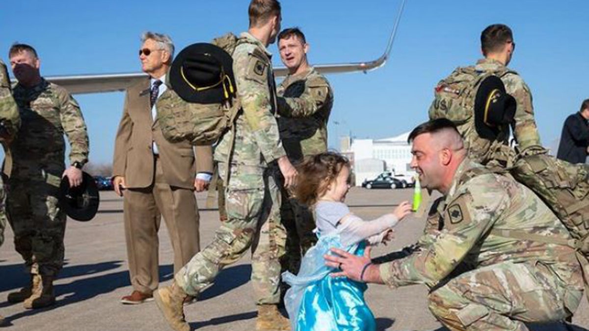 Mädchen umarmt ihren Soldatenvater