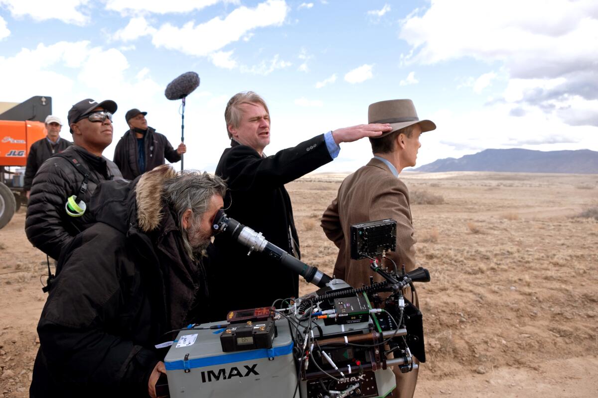 Christopher Nolan und seine Crew stehen mit Filmausrüstung auf einem Feld.