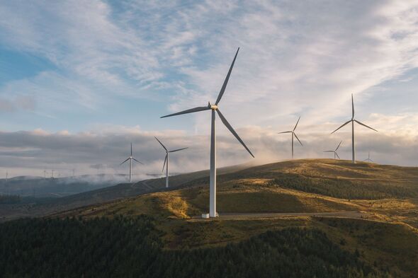 Eine Drohnenaufnahme eines Windparks bei Sonnenuntergang auf einem Hügel in Schottland