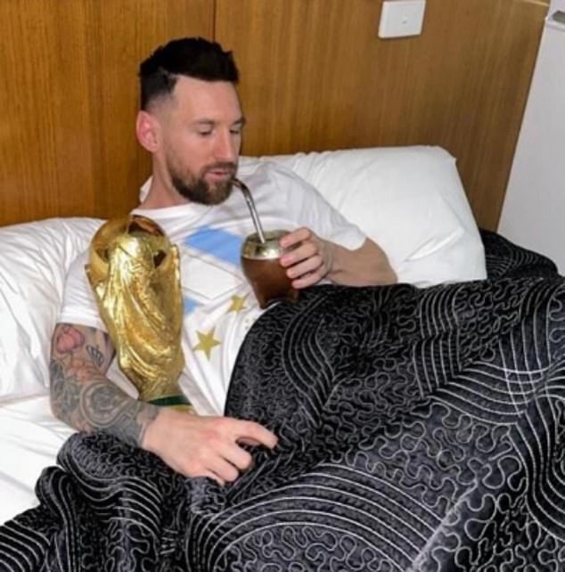 Man sieht Messi im Bett sitzen, mit der WM-Trophäe unter dem Arm und einem Mate-Kürbis in der Hand