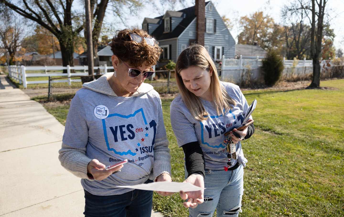 Zwei Frauen betrachten und diskutieren Rasenkarten in einer Vorstadtstraße in Ohio.