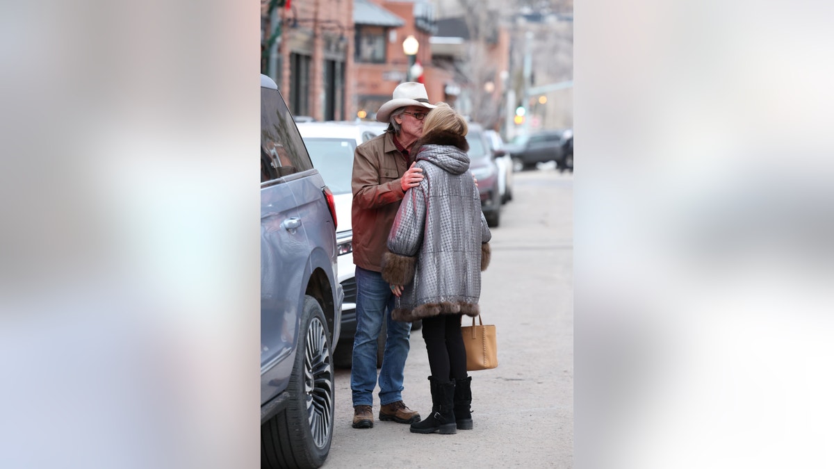Kurt Russell und Goldie Hawn küssen sich, während sie in Aspen neben Autos auf der Straße stehen