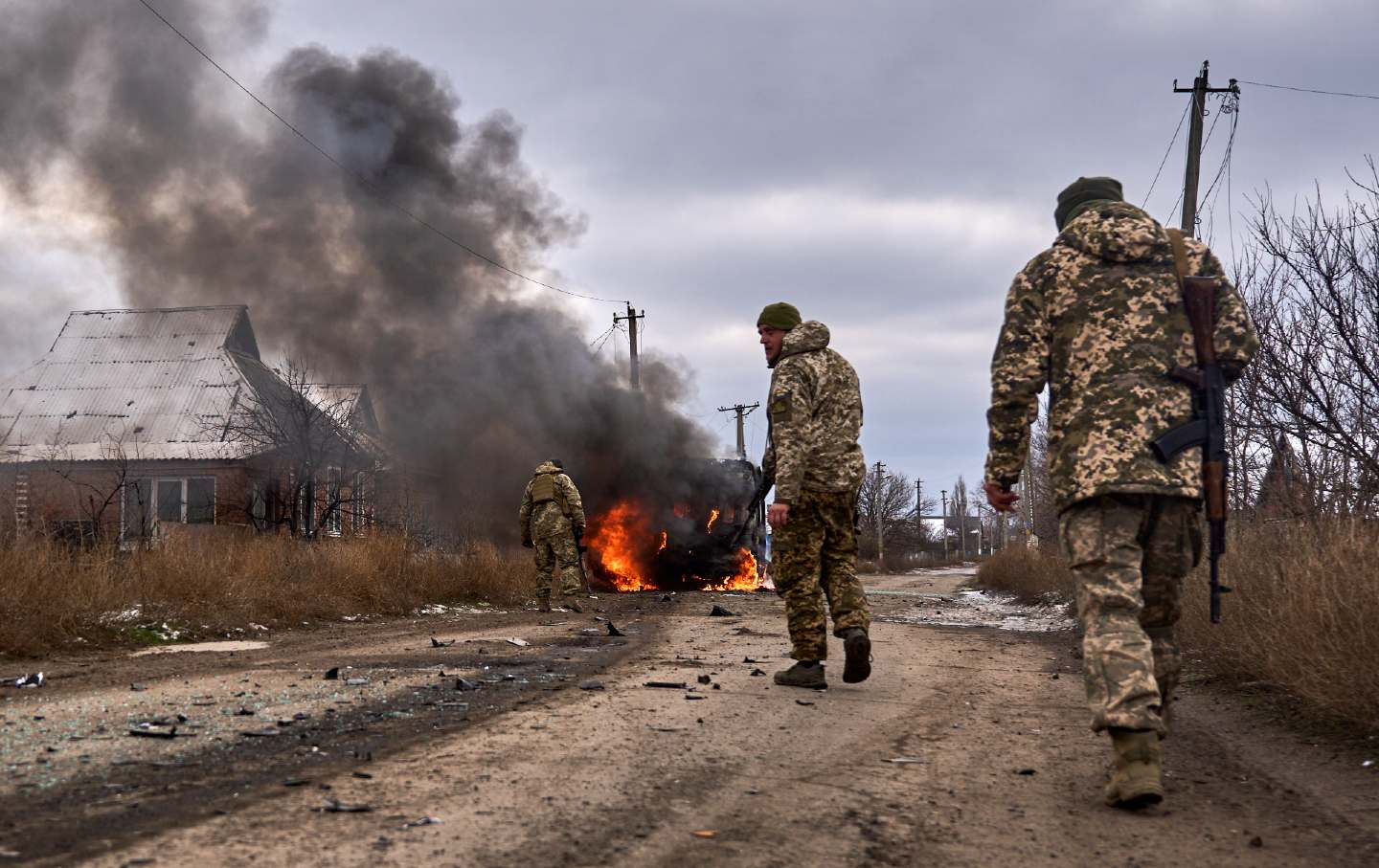 Ukrainische Soldaten kommen am 23. November 2023 in der Nähe von Bachmut in der Region Donezk in der Ukraine an einem brennenden Freiwilligenbus vorbei, nachdem ihn eine russische Drohne getroffen hatte.