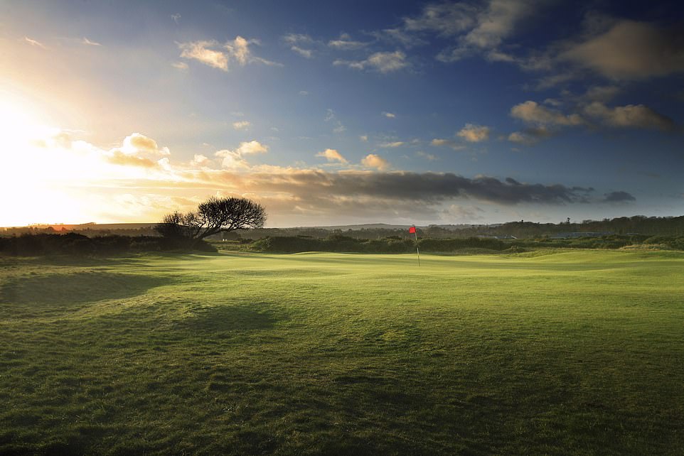 Die Sonne geht auf und die Flagge tanzt im Wind an einem wunderschönen Tag in St. Andrews – der Heimat des Golfsports