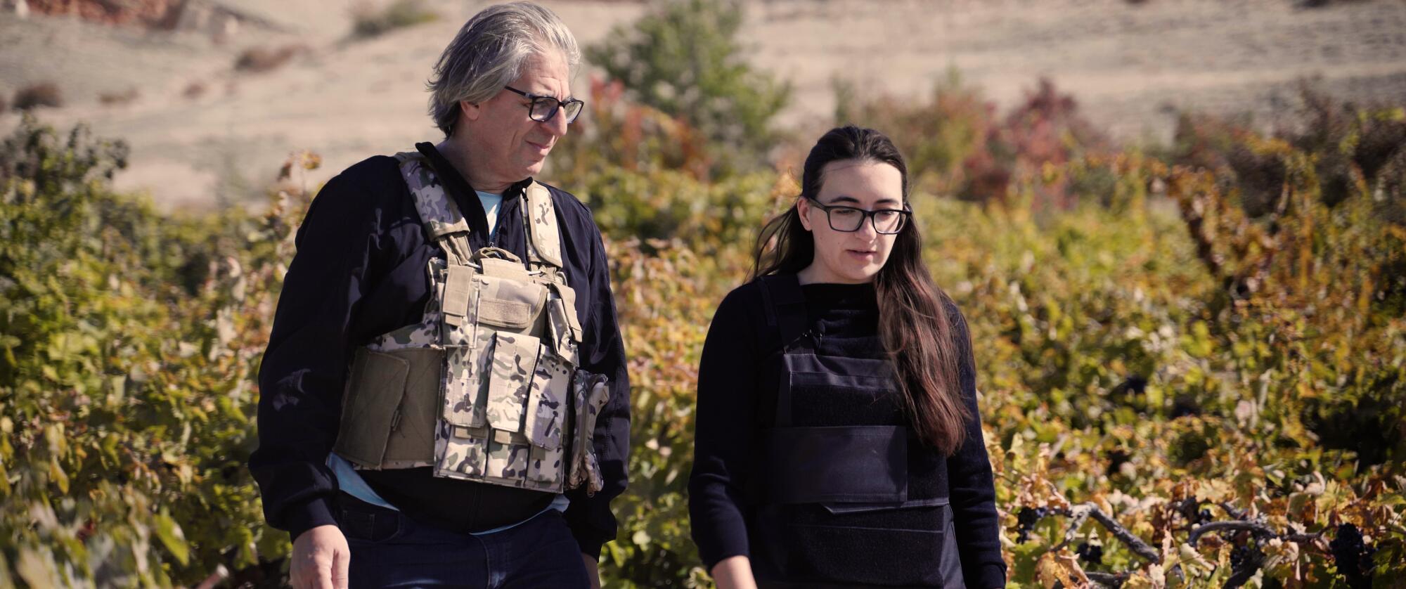 Ein Vater und eine Tochter in kugelsicheren Westen gehen in ihrem Weinberg spazieren.