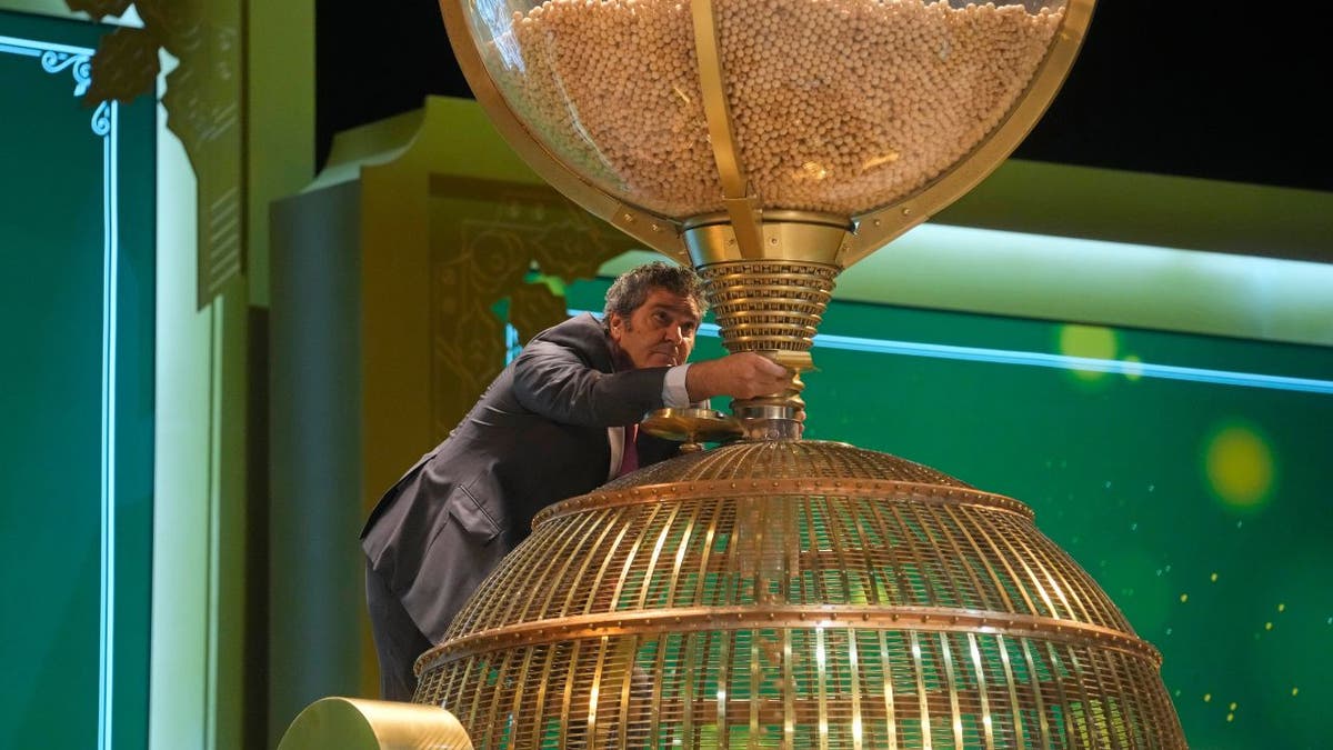 Ein Arbeiter überwacht den Moment, in dem vor einer Ziehung Lottokugeln in eine Trommel gefüllt werden