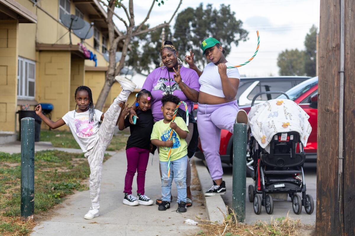 Eboni Childress, Mitte, die seit 10 Jahren in Nickerson Gardens lebt, und ihre Familie warten am Dienstag auf den Beginn der jährlichen Spielzeugaktion und des Konzerts von Top Dawg Entertainment. 