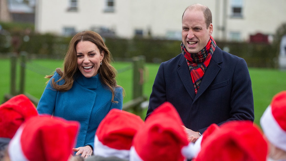 Kate Middleton und Prinz William haben sich warm angezogen und lachen über eine Schar kleiner Weihnachtsmänner