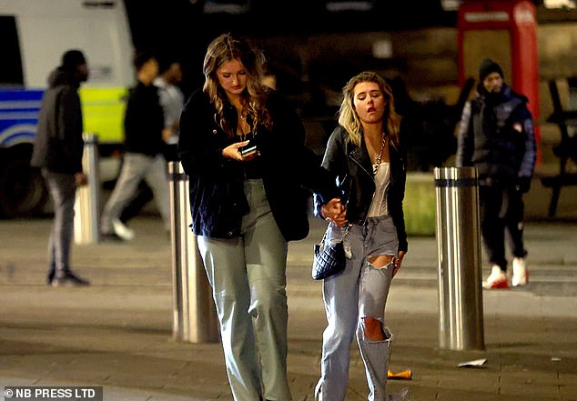 Ein Mädchen sieht abgenutzt aus, als ihre Freundin sie an der Hand führt, während sie durch Leeds streift