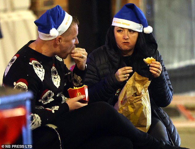 Zwei Personen mit blauen Weihnachtsmützen werden beim Essen bei McDonald's in Leeds gesehen