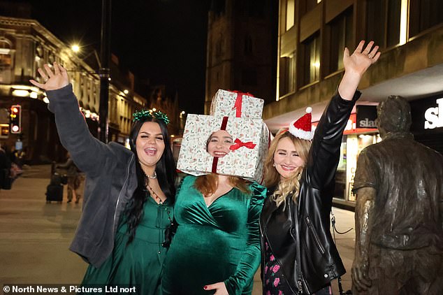 Eine schwangere Nachtschwärmerin in Newcastle, die ein Kostüm aus eingepackten Geschenken trägt, posiert mit ihren Freundinnen